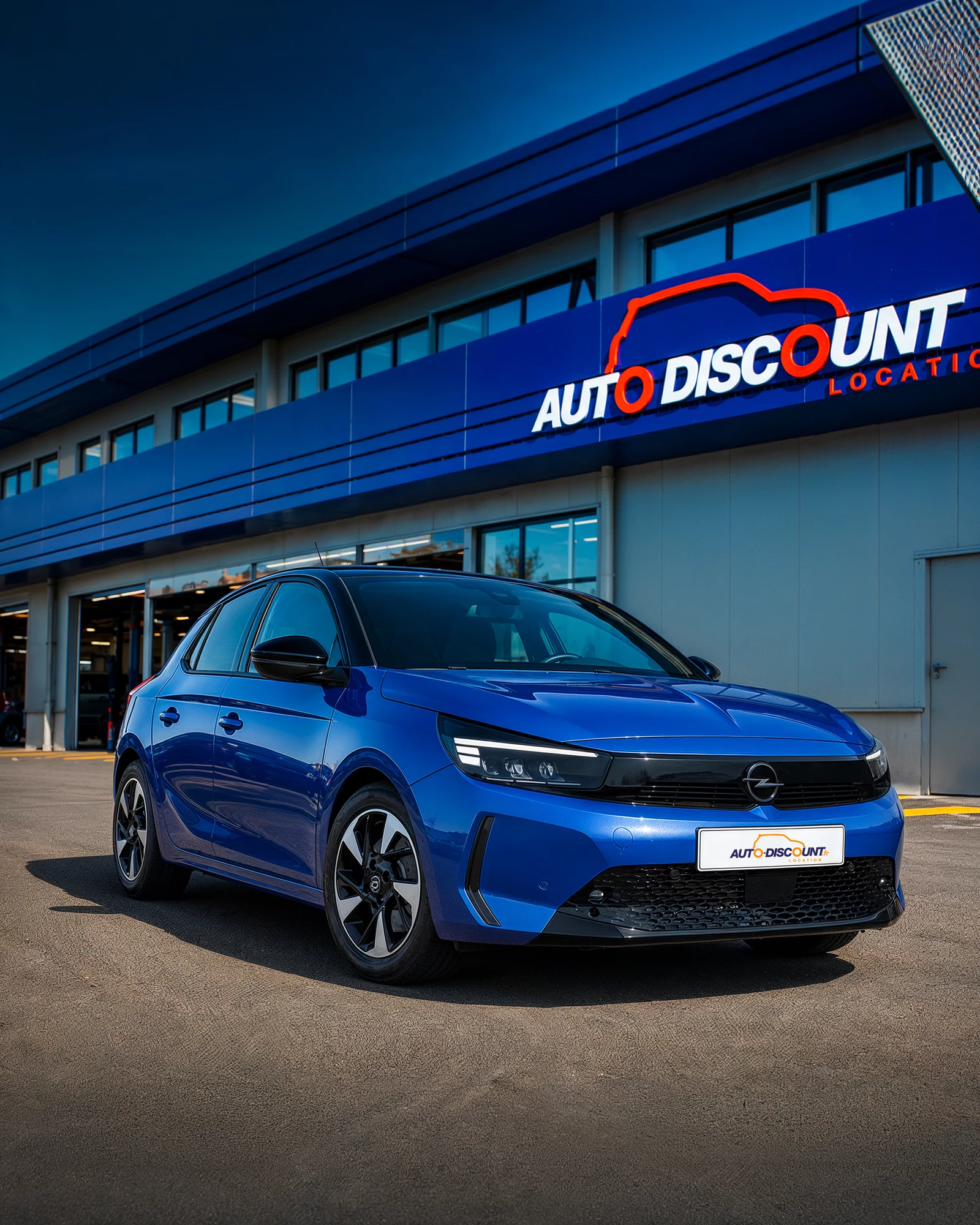 Opel Corsa bleue mise en situation devant l’agence Auto Discount